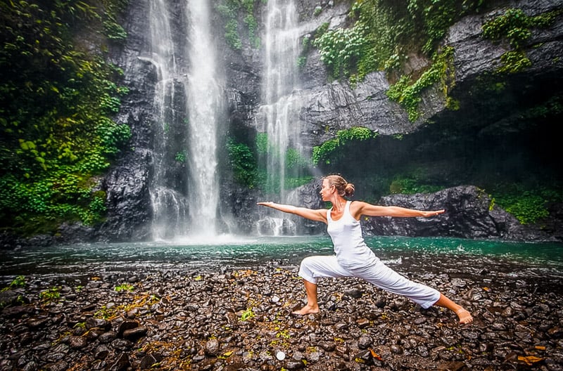 Woman doing yoga near a waterfall at one of the best wellness retreats in Bali.